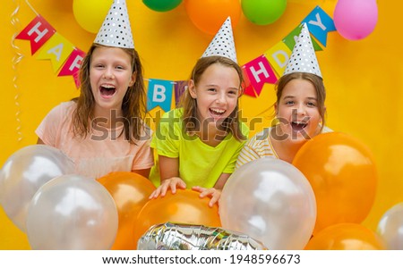 Three girls with balls on a yellow background. Children at the birthday party