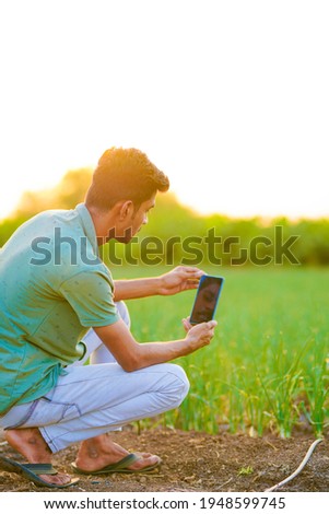 Indian agronomist taking photo in smartphone at agriculture field