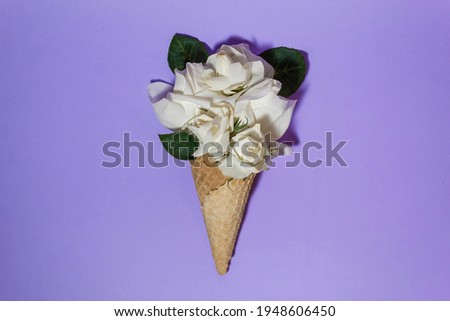 A bouquet of white roses instead of ice cream in a waffle cone on a purple background. Creative minimalism.