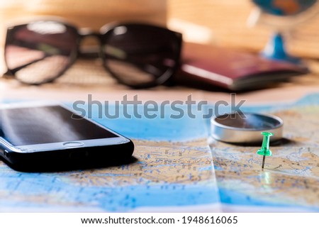 Summer weekend travel vacation accessories. Plane, passport, camera, and phone top view flat lay on map background. Copy space. Travel concept