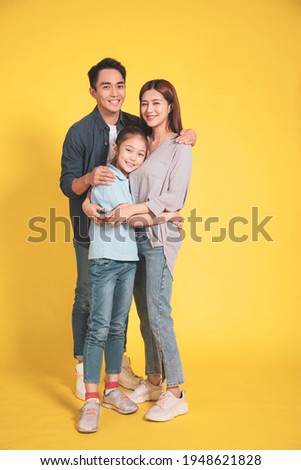 Happy Asian young family with one child standing embracing and smiling 
