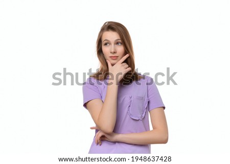 Portrait of cute thinking young woman holding arm on chin wear casual t shirt, posing over white background