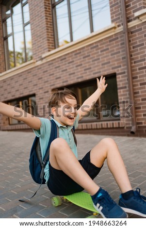Happy young boy playing on skateboard in the city, Caucasian kid riding penny board on buildings background.