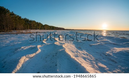 Frozen waves on the Neeme beach in Estonia. Nice sunny winter day. Frozen Baltic sea. High resolution image. Close to sunset time. Sun shining under low angle