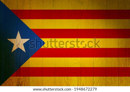 The flag of Catalonia on a grunge wooden background.