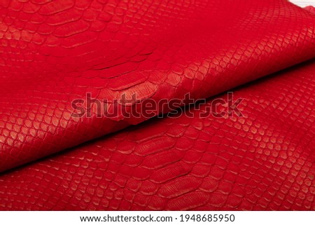 Genuine python leather dyed in red folded on a wooden table