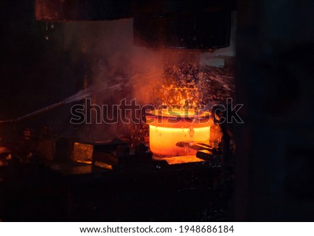 Bearing plant. Stamping of the inner ring of the bearing on mechanical press. Water cooling of the metal. Red-hot metal. Close up photo. Stepnogorsk, Kazakhstan