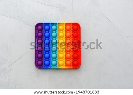 Rainbow Pop it fidget toy on a floor in home or school. Poppit -new fidget toy on empty grey copy space background. Royalty-Free Stock Photo #1948701883