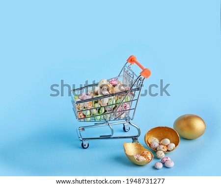 Easter sale concept. Golden easter egg fell from small shopping cart and shattered on blue background