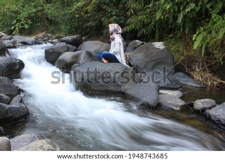 a girl is sitting in meditation on the bank of a clear river and beautiful nature.
