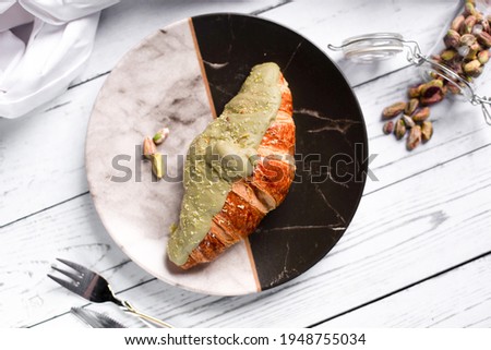 Pistachio Croissant with pistachio creamy sauce in the top and nuts on white background