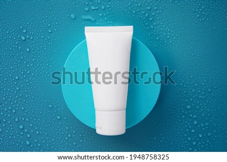 Top view Mockup facial skincare white tube product on light blue round pedestal or display with cyan blue and water droplets background. Skincare treatment for dry and sensitive skin type concept Royalty-Free Stock Photo #1948758325