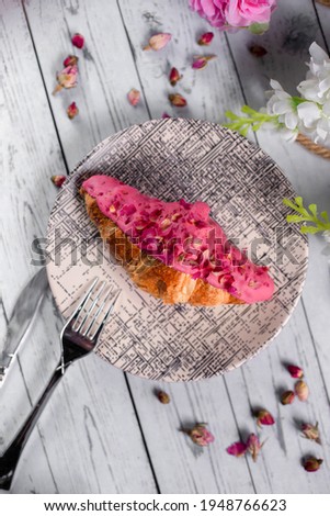 Fresh croissant with pink sauce in the top and coffee latte on white wood background, top view, close up,.