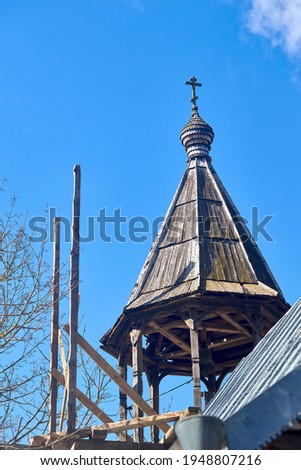 Wooden bell tower dome with orthodox cross of Church of the Beheading of St. John the Baptist in European city Grodno or Hrodna Belarus on blue sky background with cirrus clouds with copyspace.