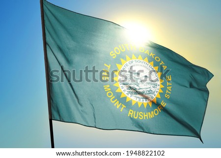 South Dakota state of United States flag waving on the wind in front of sun
