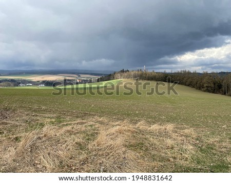View from the hill in the Czech countryside close to Tabor. New chimney of the power plant is visible behind the trees. Fields, meadows and forest are all around. The picture was taken in hilly area.