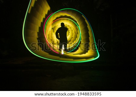 one person standing against beautiful yellow and green circle light painting as the backdrop