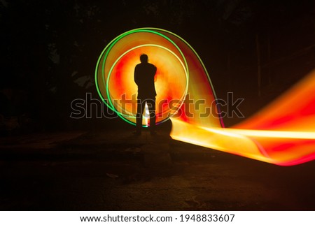 one person standing against beautiful red and yellow circle light painting as the backdrop