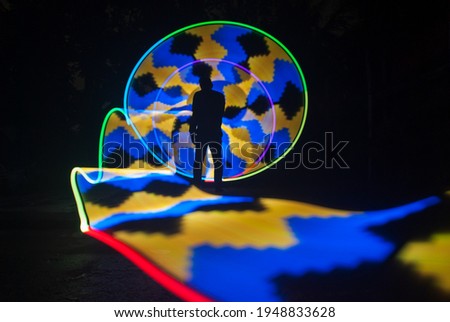 one person standing against beautiful yellow and blue circle light painting as the backdrop