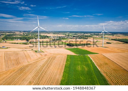 Wind turbine on field during harvest. Agriculture in Poland. Aerial view of nature