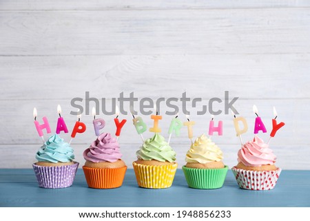 Birthday cupcakes with burning candles on blue wooden table