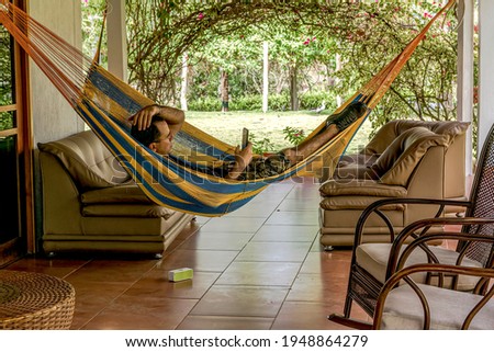 Turbaco, Bolívar, Colombia; 03-06-2021: Man rests in a hammock with his music and his cell phone.