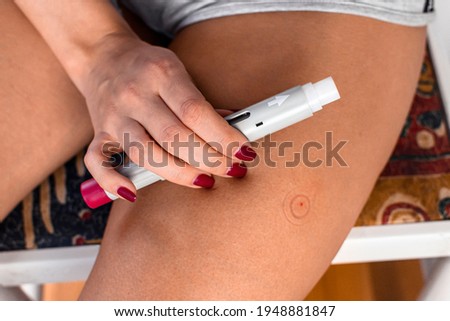 Close-up photography of stab on the thigh. The person used a shot pen injection. Medical treatment. 