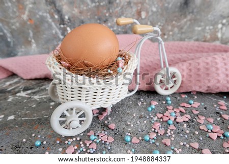 Brown chicken egg in decorative basket light bike. Beautiful greeting card for Easter holiday, gray grunge background, concept greeting picture