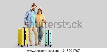 Happy smiling couple tourist traveler with luggage suitcase travel bag standing hugging looking at camera. Full body studio portrait with empty copy space aside. Vacation time, advertisement