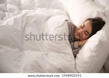 Beautiful young woman wrapped with soft blanket sleeping in bed at home Royalty-Free Stock Photo #1948903591