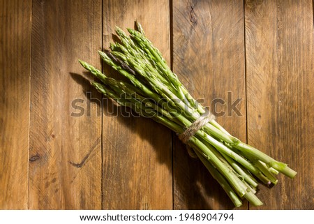 A pile of healthy country asparagus tied with a vintage string in the center of a wooden table with copy space to the right and left of the picture. Healthy, Mediterranean and vegetarian food concept.
