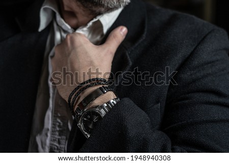 Stylish man wears wrist wooden and leather bracelets Royalty-Free Stock Photo #1948940308