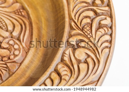 wooden plate with a carved ornament on a white background. handmade concept.