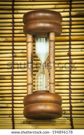 Hourglass laying on bamboo woven together.