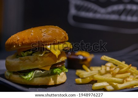 Two-layer hamburger. Ground beef burger, cheese and lettuce, with french fries and ketchup sauce
