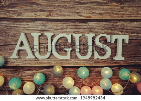 August alphabet letter with LED cotton balls on wooden background