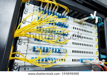 technology equipment with optical fibre cables connected to rack servers in room