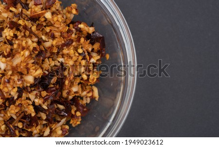 Dried chilli and garlic blended in a glass jar on a black background.