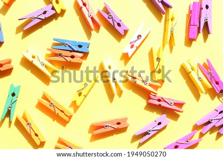 Decorative multicolored wooden clothespins on a yellow background. Flat lay composition
