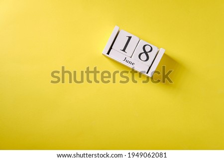 Wooden calendar on yellow background, top view, date 18 June Royalty-Free Stock Photo #1949062081