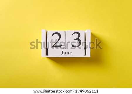 Wooden calendar on yellow background, top view, date 23 June