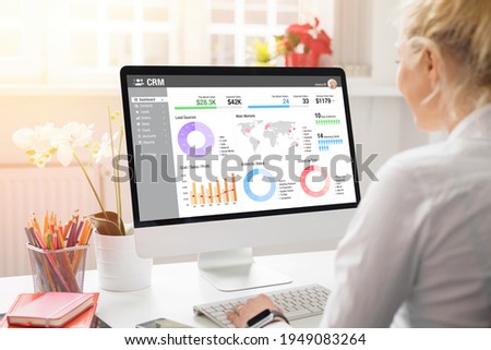 Girl working with desktop computer in office. Viewing different charts, graphs and infographics of CRM on the computer screen.