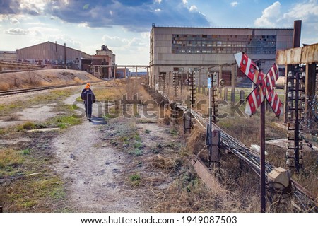 Outdated Soviet mining and processing plant. Red railroad sign and workers.