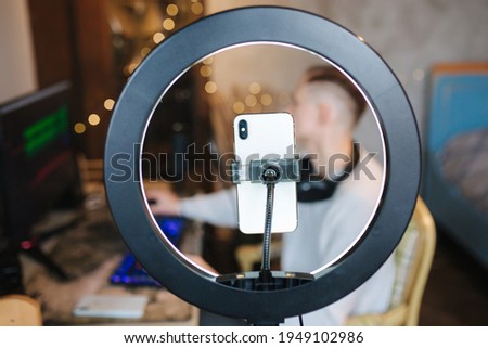 Man recording video on smartphone during the work at home on computer. Young guy recording on professional microphone speash about music. Phone in focus