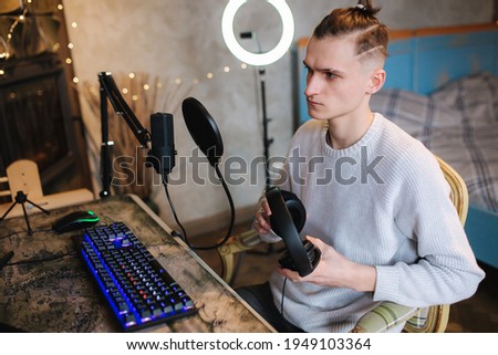 Handsome guy is recording podcast using microphone and creating content for audio blog. Man put on headphones and starting work at home. Sound equipment concept