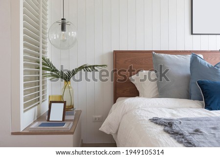 Modern style interior of blue and white bedroom with wood wall, hanging lamp and and picture frame on wall.