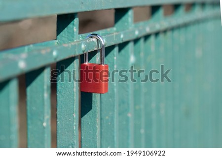 A bright orange padlock hanging on a mint green fence or rails. Romantic believes and love guarantee tradition. Isolated color.