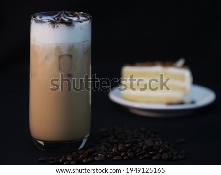 Iced latte served in the glass on black background (Low-key Picture Style) ,Ice coffee in a glass with cream poured over,Cold summer drink with tubes on a black