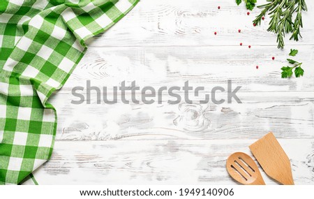 White wooden table covered with green tablecloth and cooking utensils. View from top. Empty tablecloth for product montage. Free space for your text	