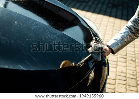Car detailing - the woman holds the microfiber in hand and polishes the car. Selective focus.